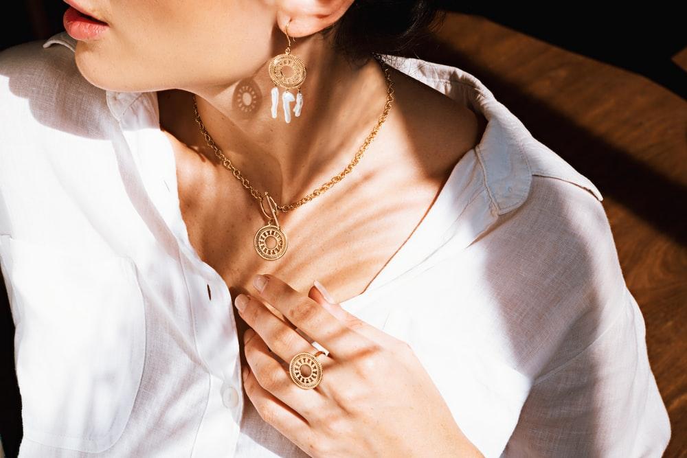 woman in white v neck shirt wearing gold necklace